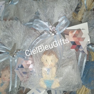 Miniatura de bebé em saco de rede branco com laço azul claro e fecho estrela, cartão branco com texto azul anexado