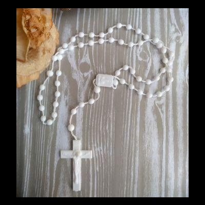 Terço branco com cruz em fundo de madeira cinza