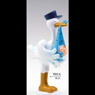 Figurinha decorativa de cegonha branca segurando bebê em pano azul