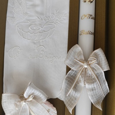 Conjunto de batismo com vela branca, toalha bordada e concha decorativa.