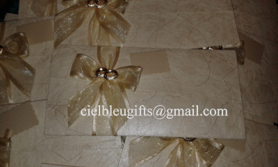 Envelopes de convite bege com laços dourados e argolas