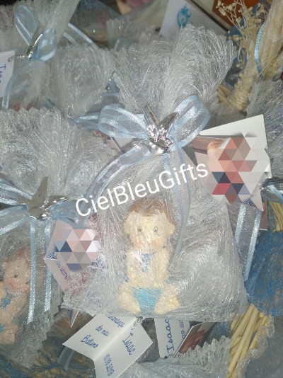 Miniatura de bebé em saco de rede branco com laço azul claro e fecho estrela, cartão branco com texto azul anexado