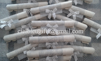 Rolos decorativos com fitas cinzentas e laços sobre tecido transparente escuro