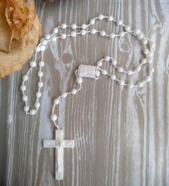 Terço branco com cruz em fundo de madeira cinza