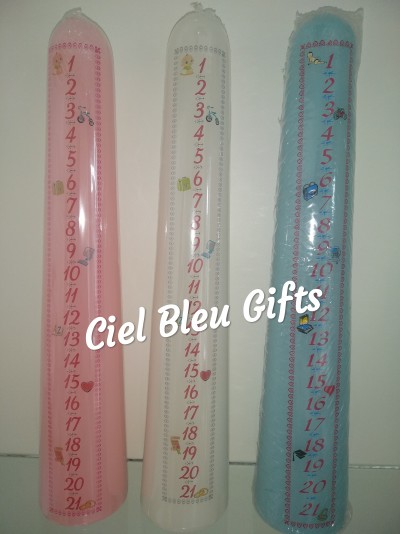 Três velas altas em embalagem plástica nas cores rosa, branco e azul com números e ícones coloridos.