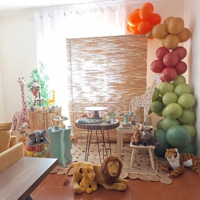 Decoração de festa infantil com balões coloridos, peluches de animais e mesas rústicas