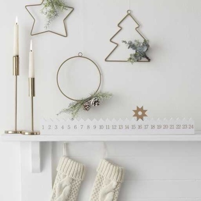 Decoração de Natal com castiçais dourados, molduras metálicas decorativas e meias de malha na prateleira branca