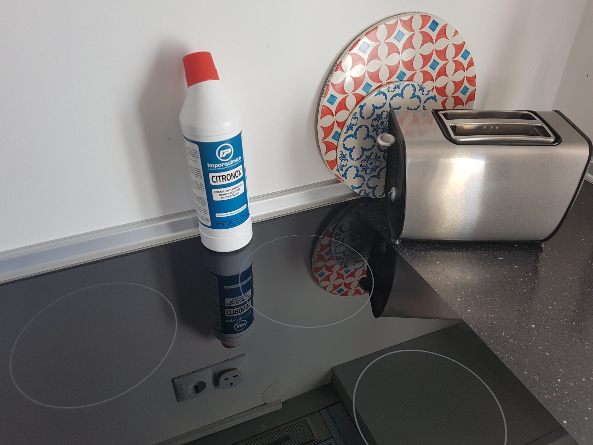 Cozinha com placa vitrocerâmica, frasco de produto de limpeza CITROLO e tostador metálico