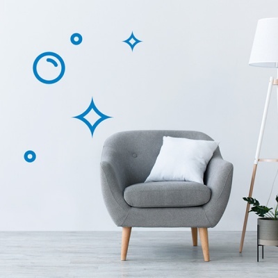 Poltrona cinzenta com almofada branca junto a candeeiro de pé e planta