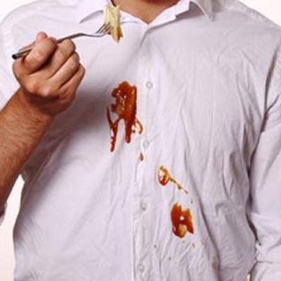 Homem com camisa branca manchada segurando garfo com comida