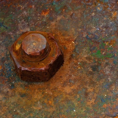 Parafuso hexagonal enferrujado numa superfície metálica oxidada