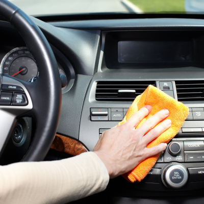 Mão a limpar painel de carro com pano de microfibra laranja