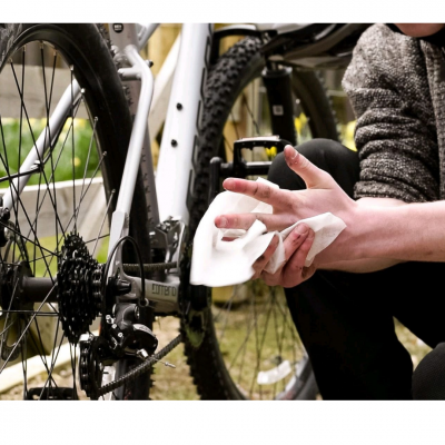 Pessoa limpando as mãos perto da roda traseira de uma bicicleta branca e preta