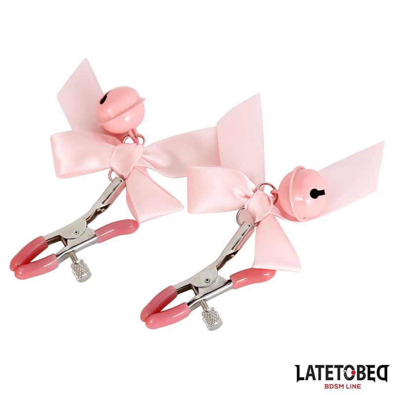 Par de prendedores metálicos rosa com laços e campainhas sobre fundo branco