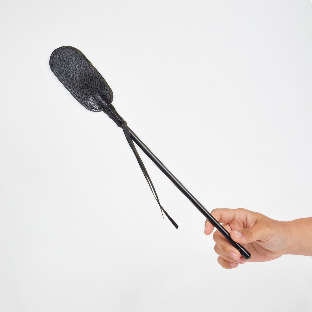 Paddle preto de couro com alça sendo segurado por uma mão