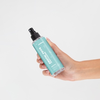Frasco spray para limpeza com rótulo azul claro e tampa preta, segurado por uma mão.