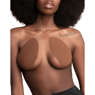 Mulher com adesivos marrons autocolantes para seios e tatuagem no ombro direito