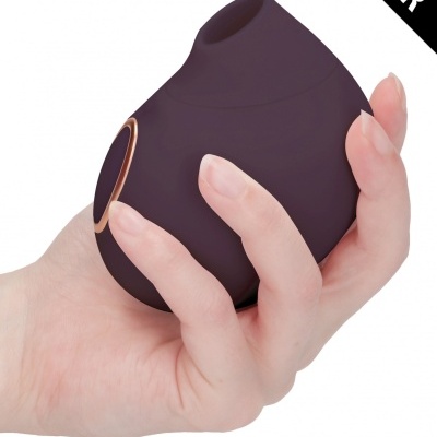 Produto eletrônico roxo escuro com botão dourado na mão de mulher