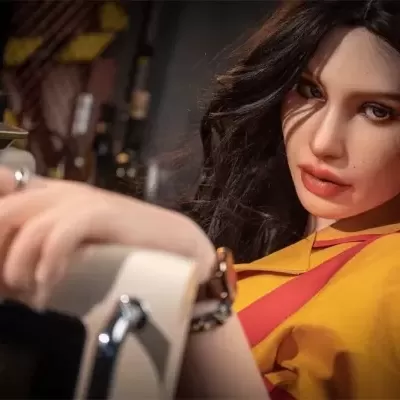 Boneca realista com camisa amarela e cabelos castanhos escuros segurando aparelho branco