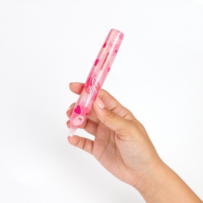 Tubo rosa de body paint com design de morangos segurado por mão feminina