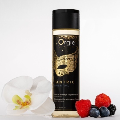 Frasco de óleo de massagem vegetal com rótulo preto e dourado, flor branca e frutos vermelhos e pretos ao lado.