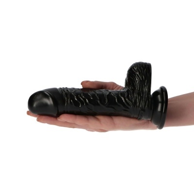 Dildo preto grande com base de ventosa sendo segurado por uma mão