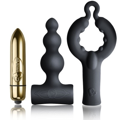Três produtos sexuais: vibrador dourado, plug anal preto e estimulador preto com anel circular