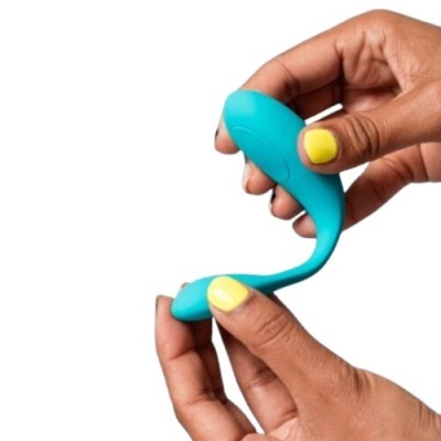 Dispositivo azul curvo em silicone segurado por mãos com unhas amarelas