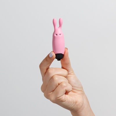 Figura cor-de-rosa em formato de coelho segurada entre os dedos