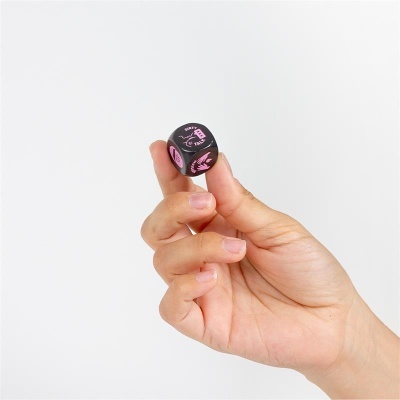 Mão segurando dado preto com texto cor-de-rosa