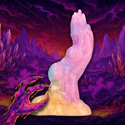 Produto de silicone rosa e bege com textura, em fundo roxo com montanhas e mão monstruosa púrpura