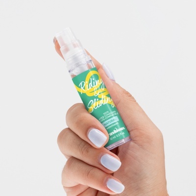 Frasco spray transparente com etiqueta colorida segurado por mão com unhas brancas