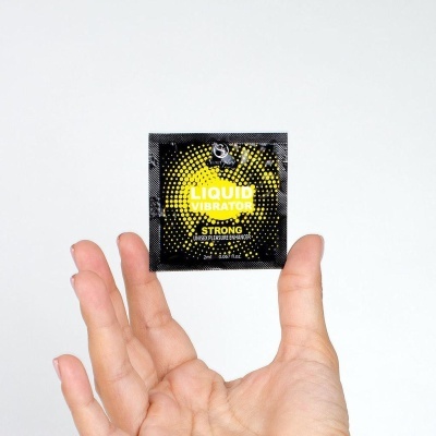 Pacote preto e amarelo LIQUID VIBRATOR com mão segurando em fundo branco