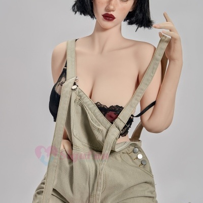 Boneca realista com salopete bege e soutien preto sentada numa cadeira