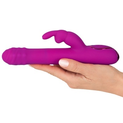 Vibrador roxo com estimulador em formato de coelho segurado por mão.