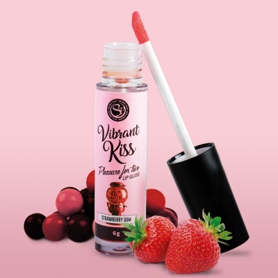 Gloss labial Vibrant Kiss Strawberry Gum com tampa preta e rótulo rosa, morangos e bolinhas vermelhas ao fundo sobre fundo rosa