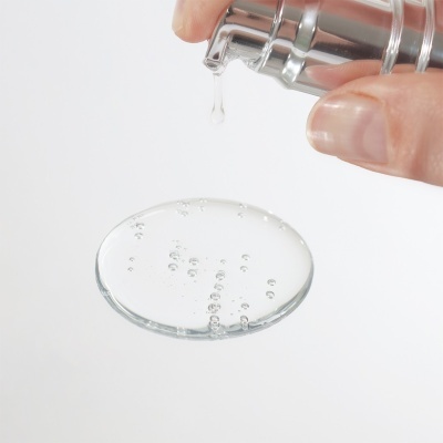 Frasco prateado com pump a dispensar líquido transparente com bolhas