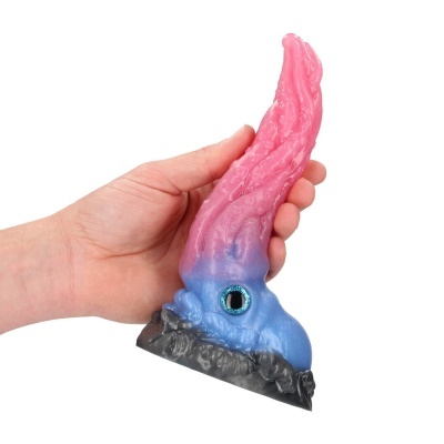 Objeto de silicone colorido com textura de tentáculo e olho decorativo, segurado pela mão