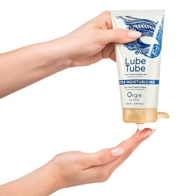 Mãos a espremer tubo de gel íntimo Lube Tube Orgie e aplicar produto