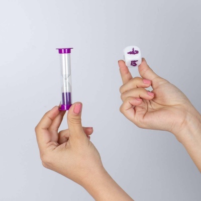 Mãos segurando um ampulheta pequena roxa e um dado branco com símbolos roxos