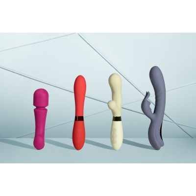 Quatro vibradores coloridos em silicone posicionados em linha sobre superfície azul clara.