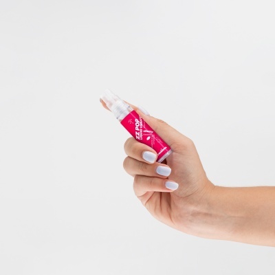 Mão segurando frasco pequeno com rótulo vermelho e texto branco