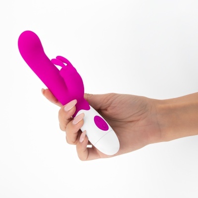 Vibrador cor-de-rosa com orelhas de coelho segurado por mão com unhas pintadas