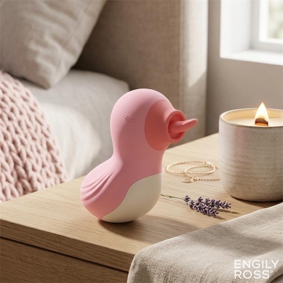 Brinquedo ou objeto decorativo em forma de pássaro cor de rosa e branco numa mesa de madeira com vela acesa e lavanda