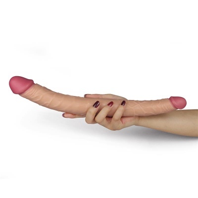 Dildo duplo em tons de pele segurado por uma mão com unhas vermelhas