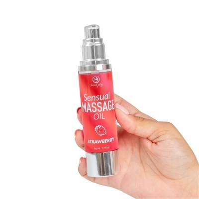 Frasco de óleo para massagem sensual aroma morango com doseador prateado na mão