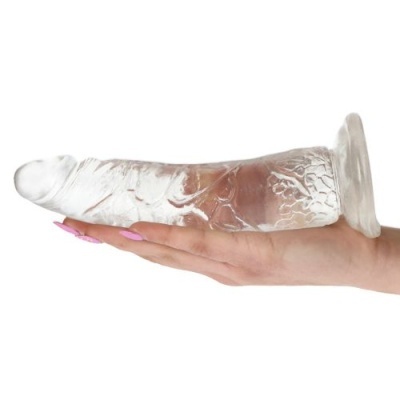 Dildo transparente em silicone segurado por uma mão com unhas pintadas de rosa
