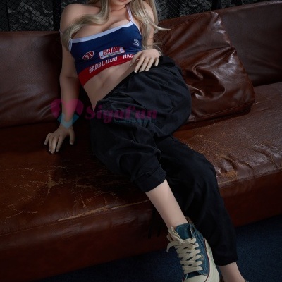 Boneca realista loira sentada em sofá de couro castanho com roupa desportiva