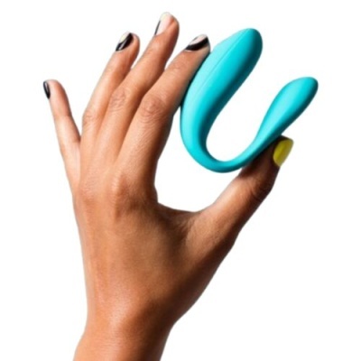 Dispositivo azul turquesa em forma curva segurado por mão com unhas pintadas.