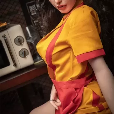 Boneca realista com vestido amarelo e vermelho com avental vermelho em ambiente interior